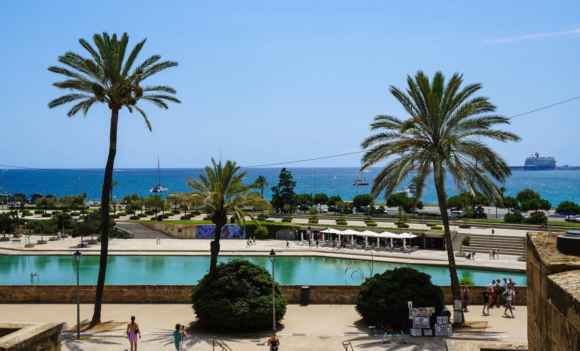 Relaxing view of a resort in Mallorca with palm trees and the sea under a summer sky.